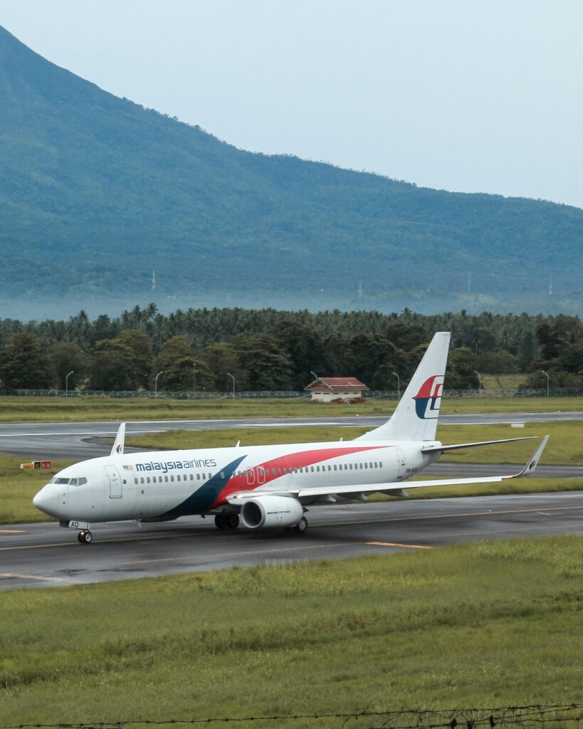 Malaysia Airlines plane on runway with mountains in Manado, Indonesia.