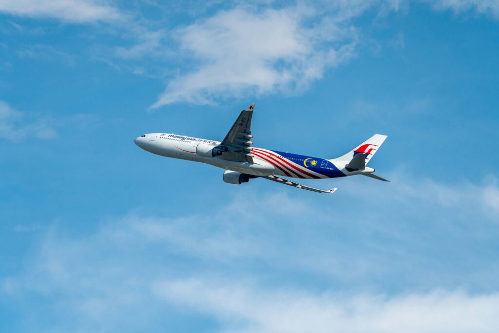 A Malaysia Airlines plane flying high with clear blue sky background. Stunning view of aviation in motion.